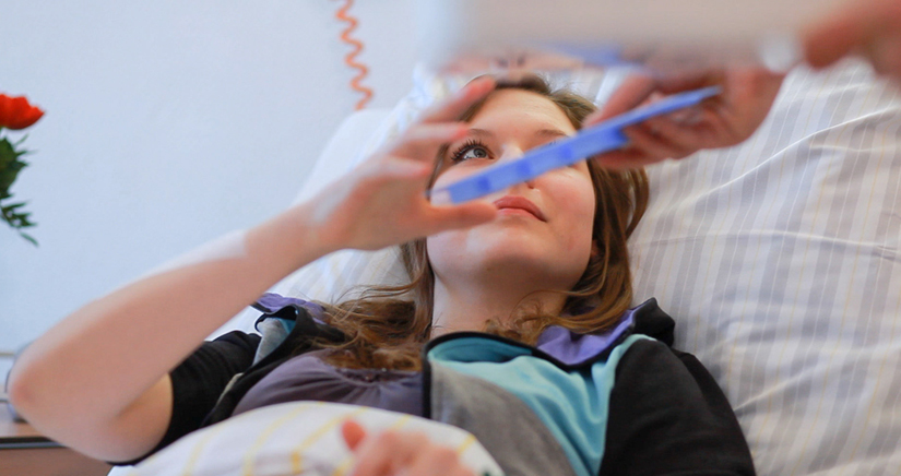 Bild Patientin liegt im Bett ihr werden die notwendigen Tablette gereicht