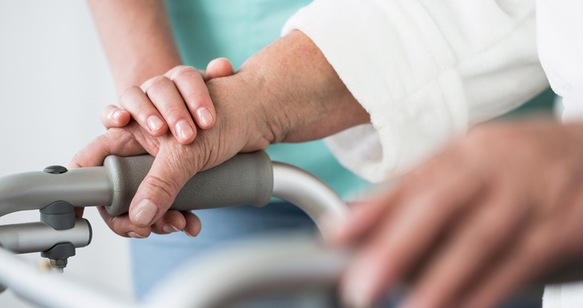 Bild Patientin schiebt ihren Rollator Pflegerin legt ihre Hand auf die Hand der Patientin